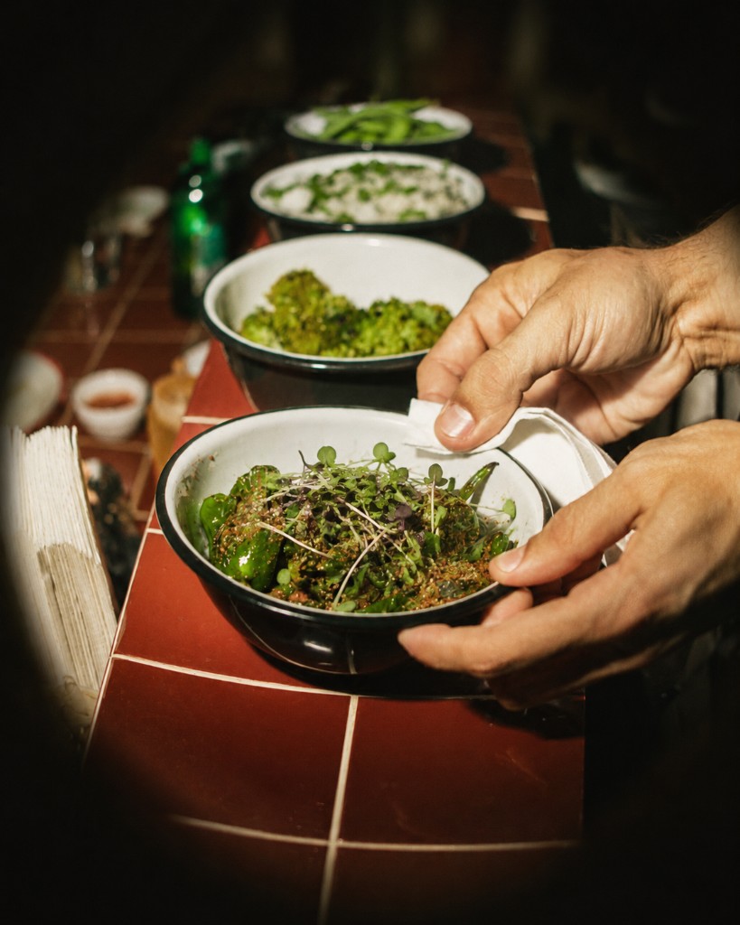 Chef wiping a bowl of spiced peppers topped with microgreens
